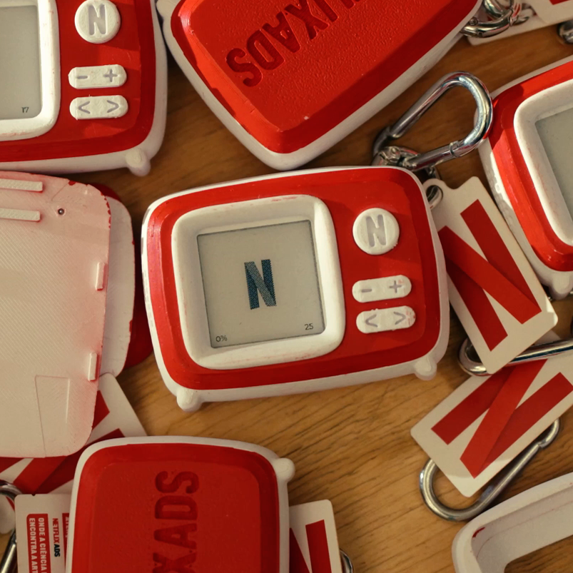 Netflix Charms: chaveiros vermelhos e brancos em forma de TV retrô, um exibindo o N da Netflix